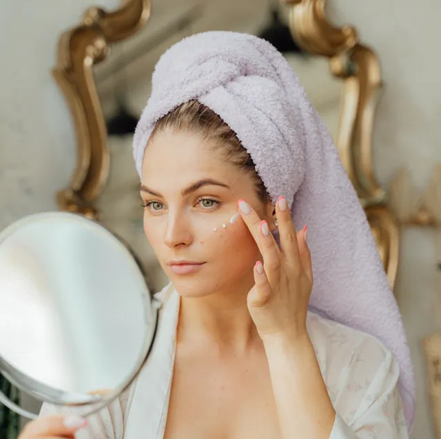 Close up beauty portrait of healthy beautiful half naked woman applying face cream looking at mirror | Femme Moderne Center for Aesthetics in Draper, Utah